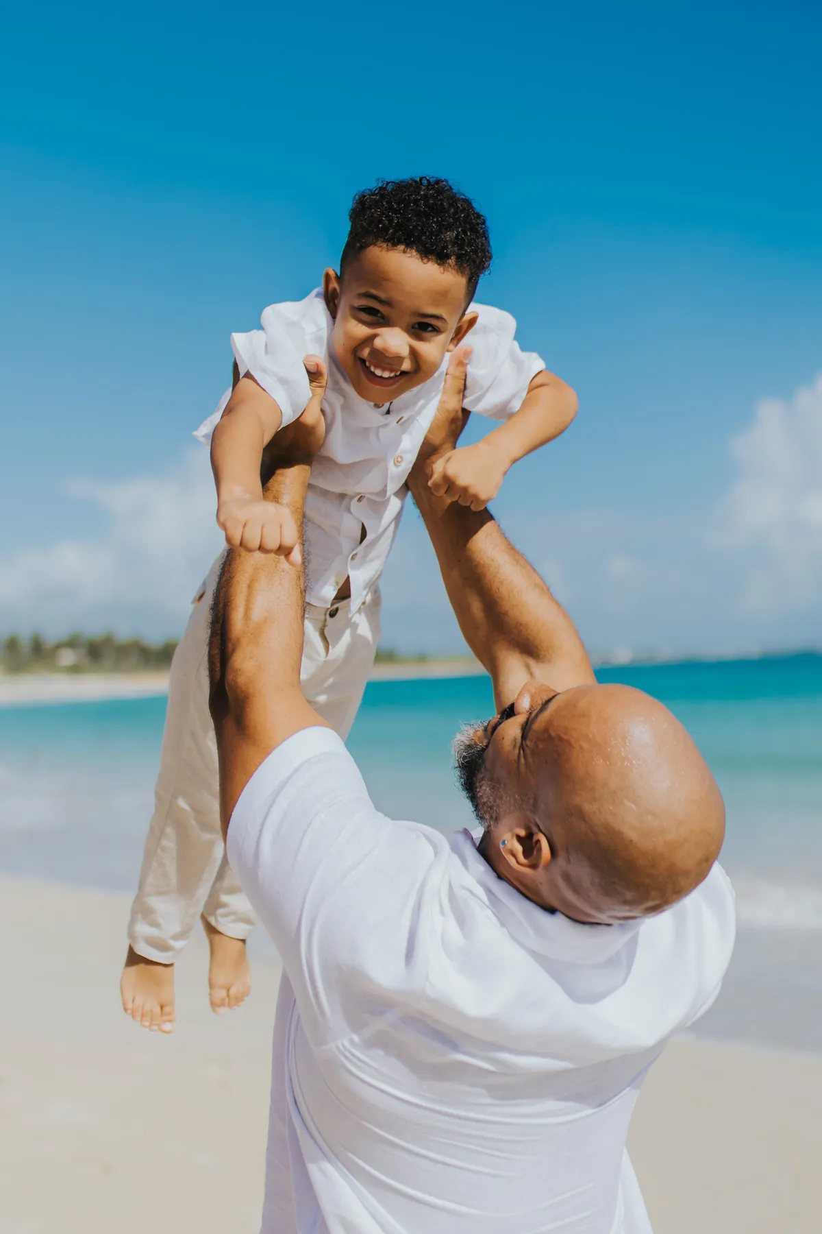 Dad lifting his laughing son into the air on a Punta Cana beach
